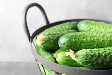 Many green fresh cucumbers in metal basket, closeup