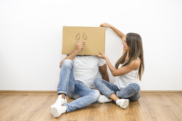 The man with a carton box on a head sit near the woman