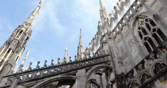 Duomo di Milano cathedral church facede. Close up on its gothic spires on blue cloudy sky background, in Milan of Italy.