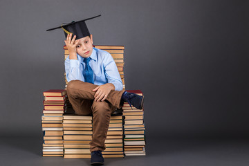 Education concept. Pensive boy sitting on a throne from books