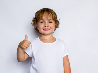 little curly redheaded boy in a white t-shirt showing thumbs up,  ok sign