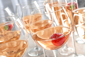 Glasses of delicious wine with strawberry on table