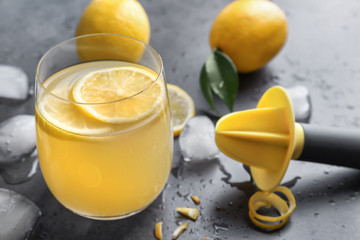 Glass of fresh lemon juice on gray table