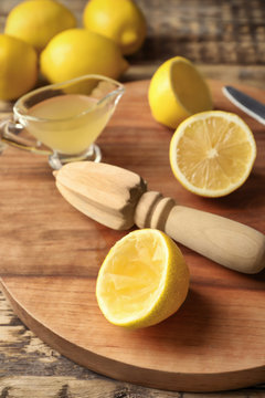 Squeezer and lemons on wooden board