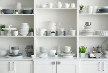 Fototapeta na wymiar White storage stand with ceramic dishware in kitchen
