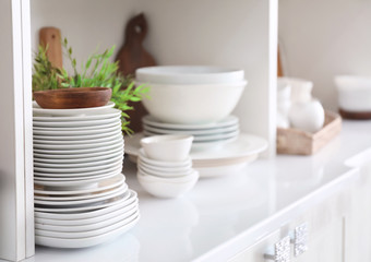 Fototapeta na wymiar White storage stand with ceramic and wooden dishware in kitchen