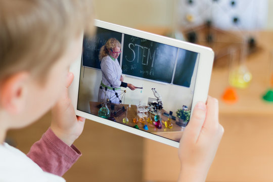 Schoolboy in the chemistry class makes photo on tablet. The teacher leads the lesson. She tell about robotics, mechanic, chemistry, biology. Modern education. Microscope and test tubes.  STEM.