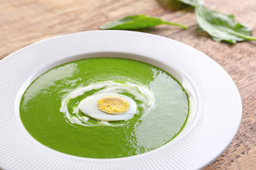 Plate with tasty spinach soup on wooden table