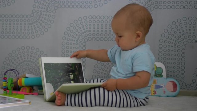 Baby boy sits and turns the pages of family photo album