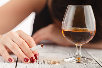 Drunk woman holding an alcoholic drink and sleeping with her head on the table (Focused on the drink, her face is out of focus)