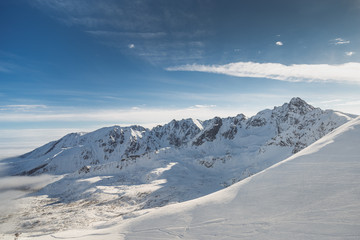 Brede luchtfoto van met sneeuw bedekte koude rotsbergen met zonnige blauwe luchten