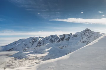 Fotobehang K2 Brede luchtfoto van met sneeuw bedekte koude rotsbergen met zonnige blauwe luchten
