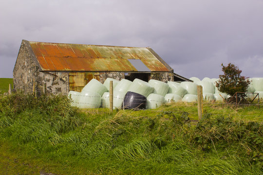 An old stone cottage with a rusting corrugated iron roof  in Northern Ireland that has been converted for farm storage uses