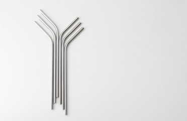 High angle view of six metal drinking straws arranged on white background