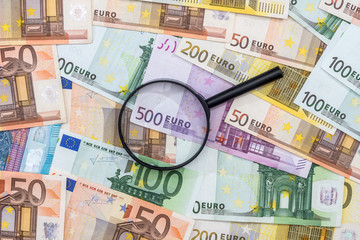magnifying glass and euro banknotes, euro coin