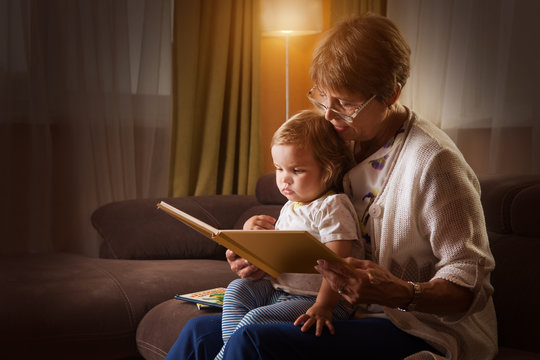 Grandmother reading a tale to her baby granddaughter. Family Reading Leisure