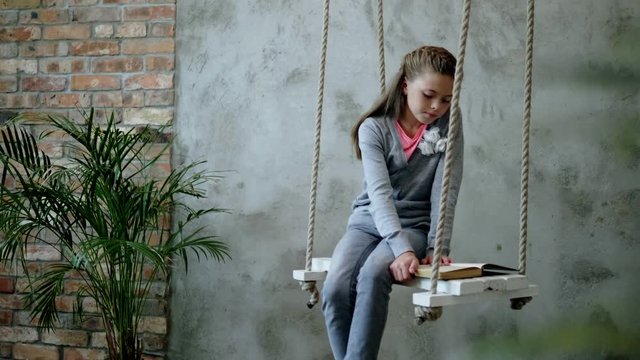 Little girl with a book on a swings