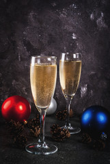 Dry Champagne in glasses, Christmas colorful balls, pine cones, New Year still life composition on dark stone background, selective focus copy space