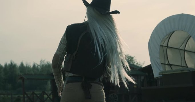 Slow motion 240fps shot of girl wearing cowboy outfit turning around with gun for shoot
