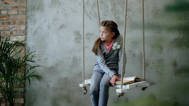 Little girl with a book on a swings