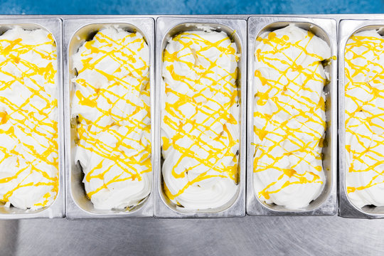 Industrial containers with vanilla ice cream and yellow sauce