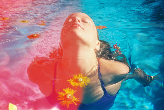 light leaked photo of girl swimming with colorful flowers in pool