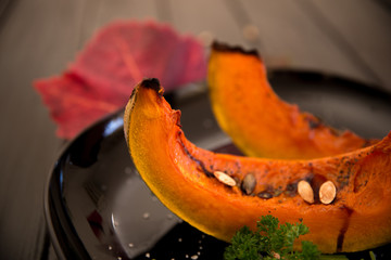 Close-up of roasted pumpkin slices and autumn leaves / Autumn concept
