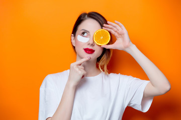 Woman using eye patch for her eyes and holding orange