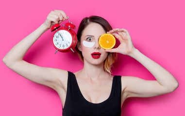 Woman using eye patch for her eyes and holding alarm clock