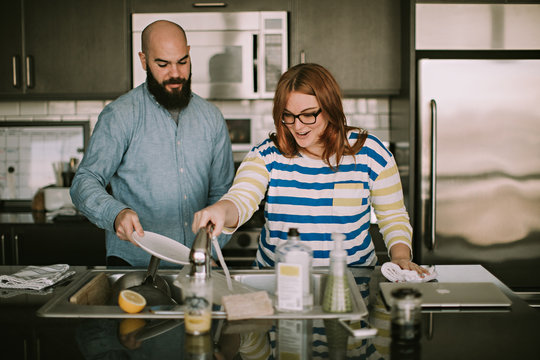 A Young Couple Does Dishes Together in Their Kitchen