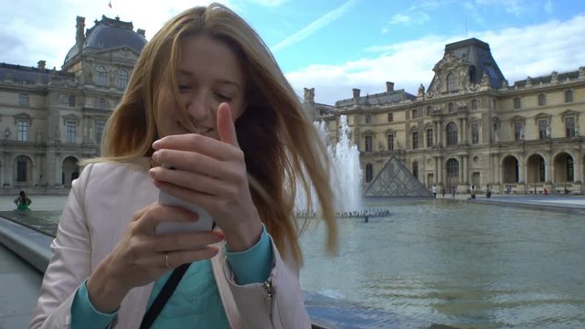 Young Happy Woman Making Selfie uses a Smartphone in Paris, the Louvre