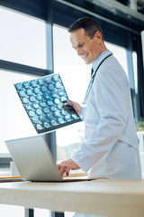 Cheerful handsome radiologist using a laptop