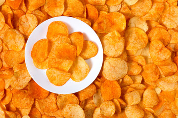 Golden Chips potato texture. Chips on a white plate standing on a big pile of chips
