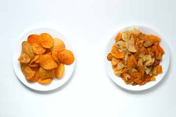 Golden potato chips. Whole and beautiful chips on one white plate and broken on a white plate next...