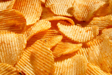 background of crispy golden chips with ribbed texture, seasoned, with sunlight. Frame for...