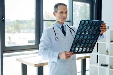 Delighted smart neurologist holding an X ray scan