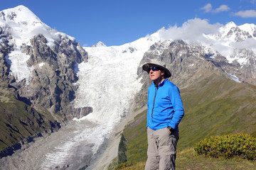 tourist in glasses stands on a background of mountains glaciers.
