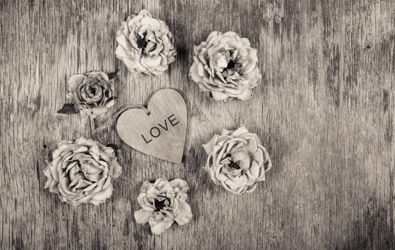Dry roses and a wooden heart. Dead flowers and love. Romantic concept. Monochrome