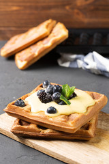 Crispy wafers with cream and berries, vertical, black background, close-up, selective focus