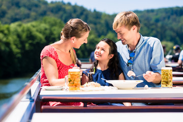 Family at lunch on river cruise with beer glasses on deck enjoying their time