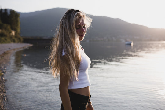 Blonde young woman relaxing at the lake at sunset