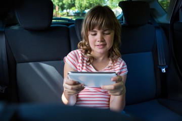 Teenage girl using digital tablet in the back seat of car - Powered by Adobe
