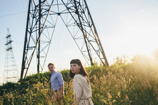 Young couple ander the power lines tower