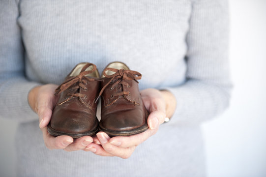 senior woman holding a pair of vintage leather child shoes