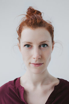 Serious mugshot of red head woman on simple white background