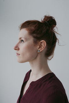 Serious profile portrait of red head woman on simple white background