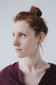 Serious portrait of red head woman on simple white background
