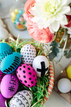Easter eggs in a basket next to fresh floral blooms