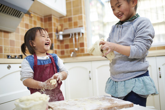 two little asian girls having fun in the kitchen
