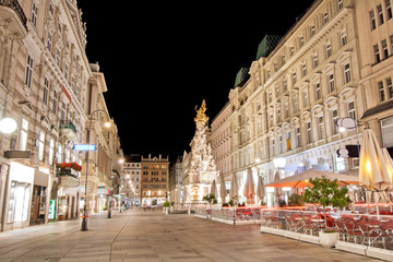 Pestsaule between illuminated buildings during night at Graben street in Vienna, Austria